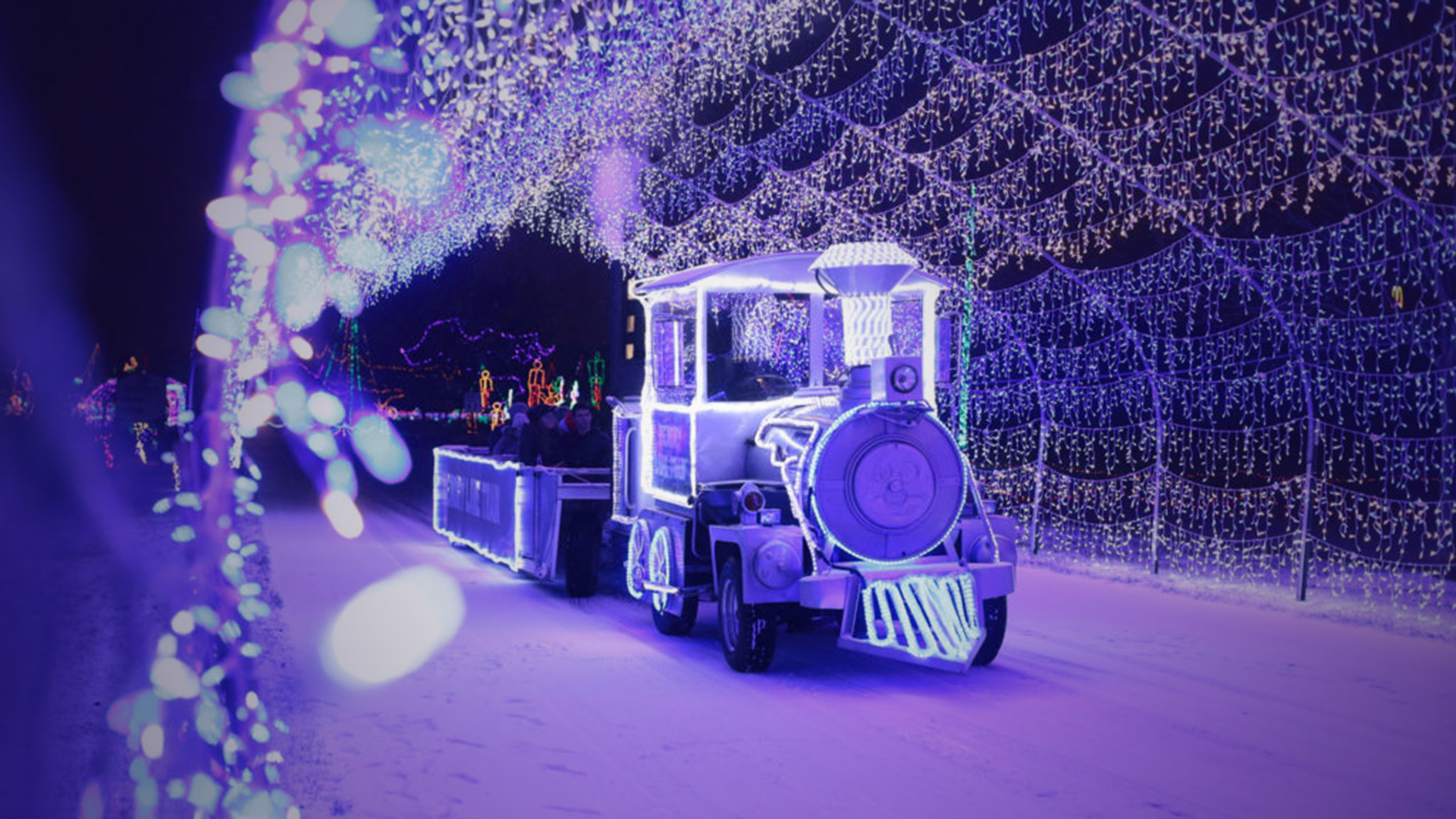 Cars driving through a tunnel of colorful holiday lights at the Christmas Lite Show at LMCU Ballpark near Grand Rapids.